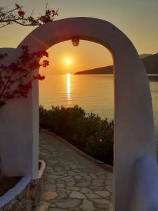 un arco che conduce a un tramonto sull'acqua di ILIDI Rock a Livadia