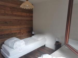 Habitación con 2 camas y pared de madera. en Gite Les Grillons en Belvédère