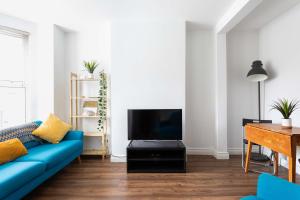 sala de estar con sofá azul y TV en Belfast City - 3 Bed Cosy Terrace Home - Hip and Trendy Ormeau Road en Belfast