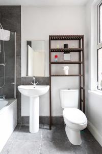 La salle de bains est pourvue de toilettes, d'un lavabo et d'un miroir. dans l'établissement Belfast City - 3 Bed Cosy Terrace Home - Hip and Trendy Ormeau Road, à Belfast