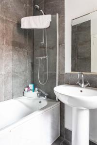 La salle de bains est pourvue d'un lavabo blanc et d'une baignoire. dans l'établissement Belfast City - 3 Bed Cosy Terrace Home - Hip and Trendy Ormeau Road, à Belfast