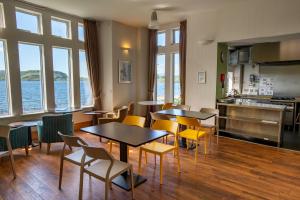 a restaurant with tables and chairs and a kitchen and water at Oban Youth Hostel in Oban