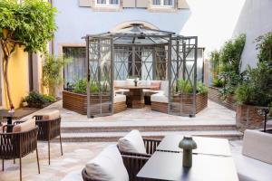 an outdoor patio with a gazebo and tables and chairs at Hotel Le Colombier in Colmar