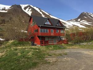 a large red house with a mountain in the background at Solbakki in Flateyri