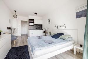 a white bedroom with a large bed and a kitchen at Modern Riverside Studio with Free Parking in Budapest