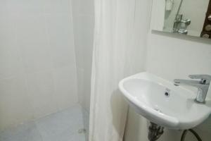 a white bathroom with a sink and a mirror at RedLiving Apartemen Royal Sentul Park - Budi Property in Cikeas