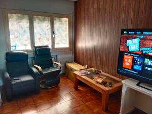 a living room with two chairs and a flat screen tv at Chalet adosado con jardín in Cebreros