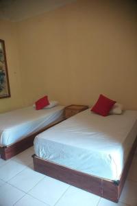 2 bedden met rode kussens in een kamer bij Nushe Hostel in Nusa Penida