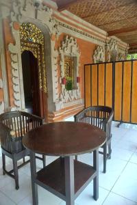 een houten tafel en twee stoelen voor een gebouw bij Nushe Hostel in Nusa Penida