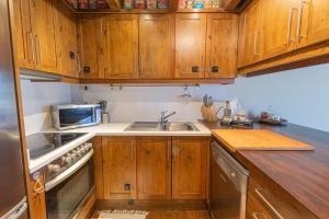 a kitchen with wooden cabinets and a sink and a microwave at Apartament les Carrerades in Estavar