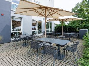 eine Terrasse mit Tischen, Stühlen und Sonnenschirmen in der Unterkunft B&B Hotel Schweinfurt-Süd in Schweinfurt