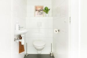 a white bathroom with a toilet and a sink at Luxe Vakantiehuis Grove Den Veluwe in Nunspeet +30 photos