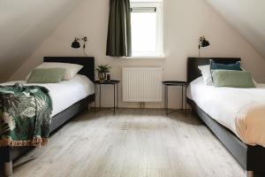 a attic bedroom with two beds and a window at Luxe Vakantiehuis Grove Den Veluwe in Nunspeet