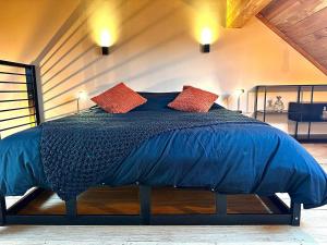 1 dormitorio con 1 cama azul y 2 almohadas rojas en Hour House - Esc'Appart, en Houyet