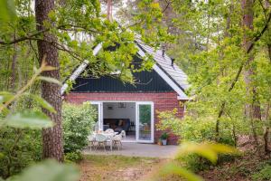 een rood bakstenen huis met een patio in het bos bij Luxe Vakantiehuis Grove Den Veluwe in Nunspeet