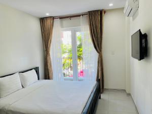 a bedroom with a white bed and a window at Kosmos Phu Quoc Apart Hotel in Phú Quốc