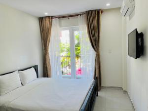 a bedroom with a white bed and a window at Kosmos Apart Hotel Phu Quoc - Night market & Walkin to beach in Phú Quốc