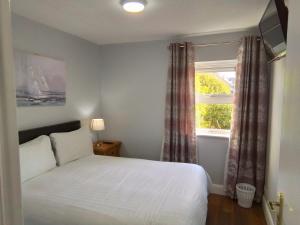a bedroom with a white bed and a window at Wild Atlantic Accommodation 70 Burnside in Letterkenny