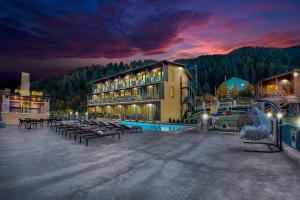 un gran edificio con bancos y piscina por la noche en Solo Grand Boshuri Hotel Wellness Resort 