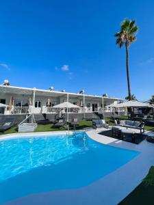 une grande piscine avec des chaises et un bâtiment dans l'établissement Tajinaste Beach Gay Men Only, à Playa del Ingles