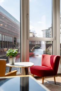 einen roten Stuhl und einen Tisch in einem Zimmer mit Fenster in der Unterkunft Ruby Lotti Hotel Hamburg in Hamburg