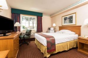 a hotel room with a bed and a flat screen tv at Ramada by Wyndham Portland in Portland
