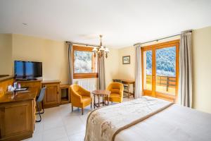Abba Ordino Babot Hotel في أوردينو: غرفة نوم بسرير ومكتب وتلفزيون