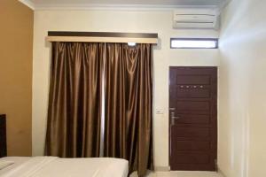 a bedroom with a bed and a brown door at RedDoorz Syariah @ Jalan Jendral Sudirman Pekanbaru in Pekanbaru