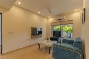 uma sala de estar com um sofá, uma mesa e uma televisão em Lavish Apartments with Swimming Pool near Candolim Beach em Marmagao
