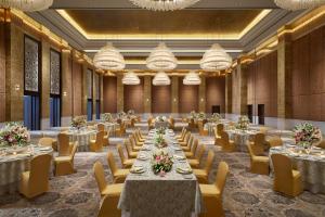 a large banquet hall with tables and chairs and chandeliers at The Leela Gandhinagar in Gandhinagar