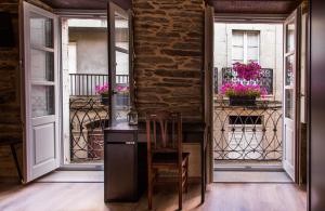 Zimmer mit einem Schreibtisch und einem Balkon mit Blumen in der Unterkunft Casa Baran in Sarria