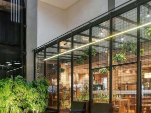 a restaurant with large windows and plants at Mercure Belo Horizonte Vila da Serra in Belo Horizonte