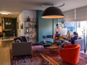 un grupo de personas sentadas en una sala de estar en Novotel Antwerpen en Amberes