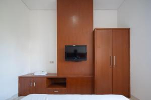 um quarto com uma televisão e um armário de madeira em Cove Sky City Home em Bandung