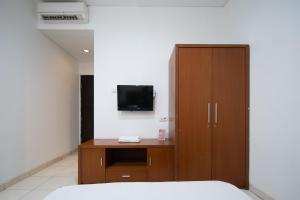 um quarto com uma cama e um armário com uma televisão em Cove Sky City Home em Bandung