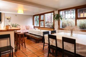 a dining room with a table and chairs and windows at La Justina Hostel in San Carlos de Bariloche