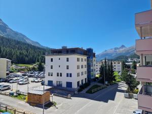 un edificio en un estacionamiento con montañas en el fondo en Apartment Via Surpunt - Casa - 5 Rooms, en St. Moritz