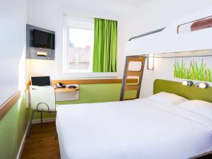 a bedroom with a bed and a desk with a laptop at ibis budget Campo Grande in Campo Grande