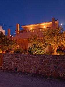a building with a stone wall in front of it at Calma in Perdika