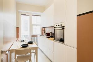 una cocina con armarios blancos y una mesa con sillas. en Easylife - Luminosa dimora in Sant'Ambrogio, en Milán