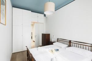 una camera da letto con un grande letto con lenzuola bianche di Easylife - Luminosa dimora in Sant'Ambrogio a Milano