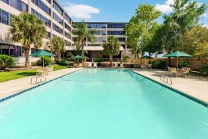 uma grande piscina com cadeiras e guarda-sóis em frente a um edifício em La Quinta by Wyndham New Orleans Airport em Kenner