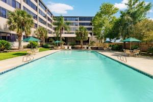 a large pool with chairs and umbrellas in front of a building at La Quinta by Wyndham New Orleans Airport in Kenner