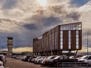 クライストチャーチにあるNovotel Christchurch Airportの駐車場にたくさんの車を停めた建物