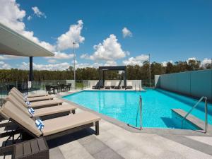 a pool with chaise lounge chairs at Pullman Brisbane Airport in Brisbane