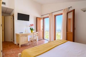 1 dormitorio con cama y escritorio con ventana en Hotel Marie Claire en Lanusei