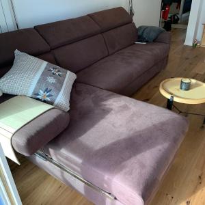 a brown couch in a living room with a table at WEF 2025 Ferienwohnung, 1min von Kongresshaus in Davos