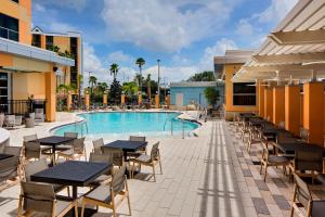 un patio del hotel con mesas y sillas y una piscina en Hyatt House across from Universal Orlando Resort en Orlando