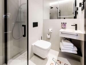 a white bathroom with a toilet and a shower at Tribe Riga City Center in Rīga