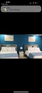 two beds in a room with a blue wall at Bayfront in Portmore